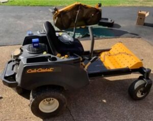 A black and yellow lawn mower sitting on top of a road.